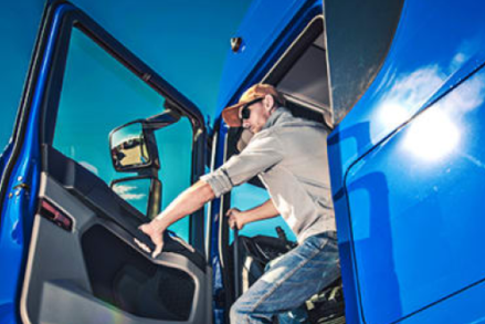 Photograph of a man getting out of a large blue truck
