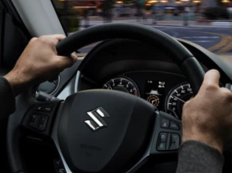 Image of someone with their hands on the steering wheel of a Suzuki.