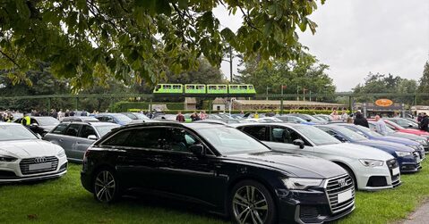 Row of Audi cars lined up under trees with Beaulieu monorail passing overhead during Simply Audi 2025.