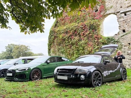 Green Audi RS and black Audi TT parked beside historic stone ruins at Beaulieu Motor Museum during Simply Audi 2025.