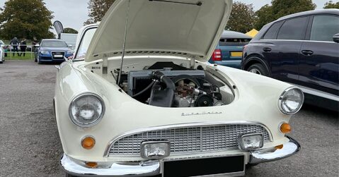 Vintage white Auto Union coupé with bonnet open, displayed at Simply Audi 2025 in Beaulieu Motor Museum grounds.